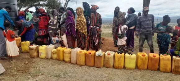 Frauen warten in Afrika mit Kanistern auf frisches Wasser an einer Pumpe