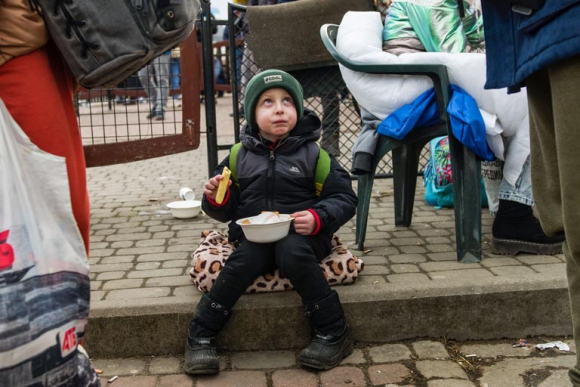 Ein Kind aus der Ukraine erhält auf der Flucht etwas zu essen