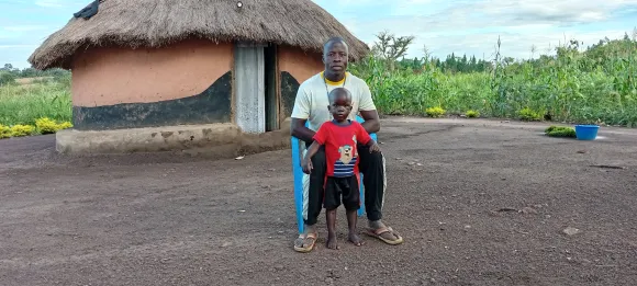 Kind mit Vater vor Haus in Afrika