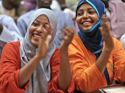 Frauen mit Kopftuch lachen und klatschen