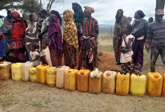 Frauen warten in Afrika mit Kanistern auf frisches Wasser an einer Pumpe