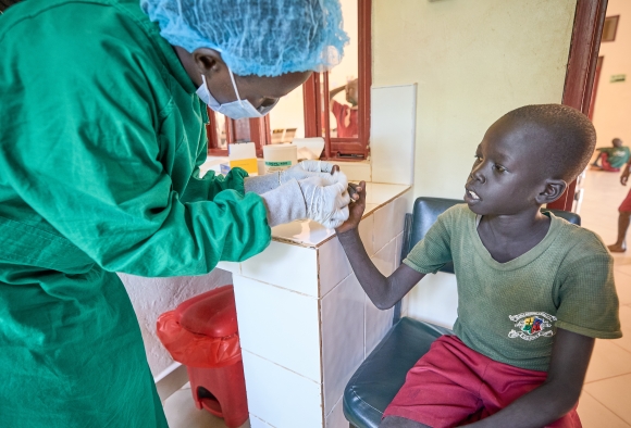 ein Arzt macht einen Malariatest in Afrika, ein Kind erhält medizinische Hilfe